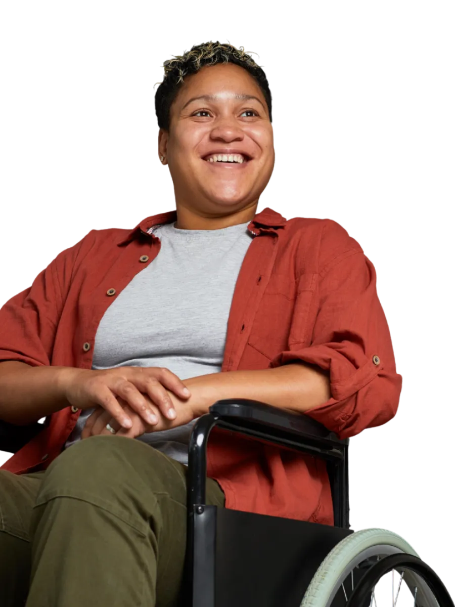 Smiling person in a wheelchair wearing a red shirt and olive pants looking happy and relaxed