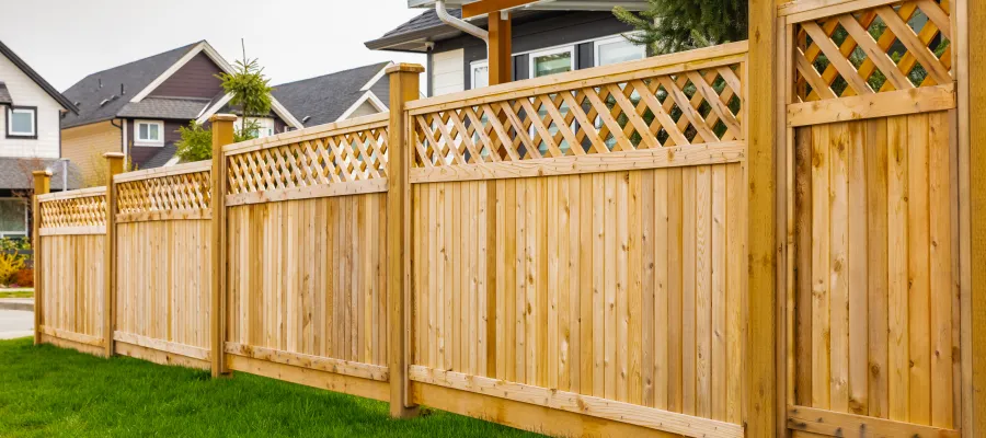 A well-maintained wooden fence with lattice design, enhancing a home's outdoor aesthetic in a suburban neighborhood.