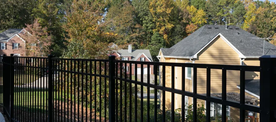 Black metal railing overlooking suburban homes and trees in autumn foliage.