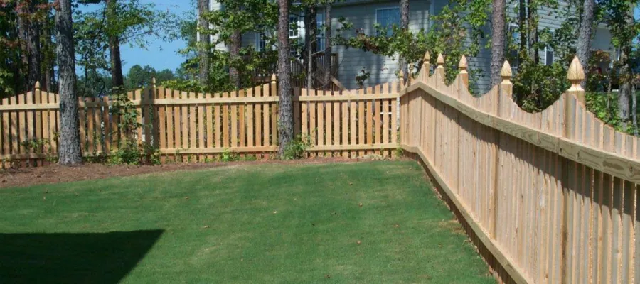 a fenced yard with a wooden gate and a building in the background