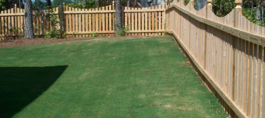 A well-maintained lawn bordered by a decorative wooden fence in a residential setting.