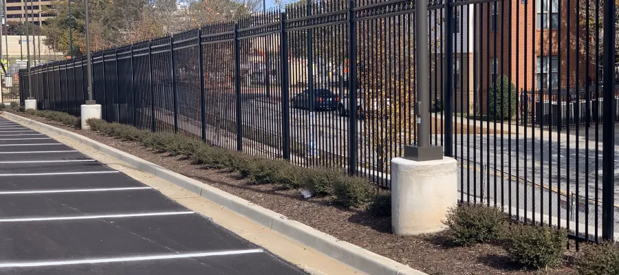 a black gated off area with a road and buildings in the background