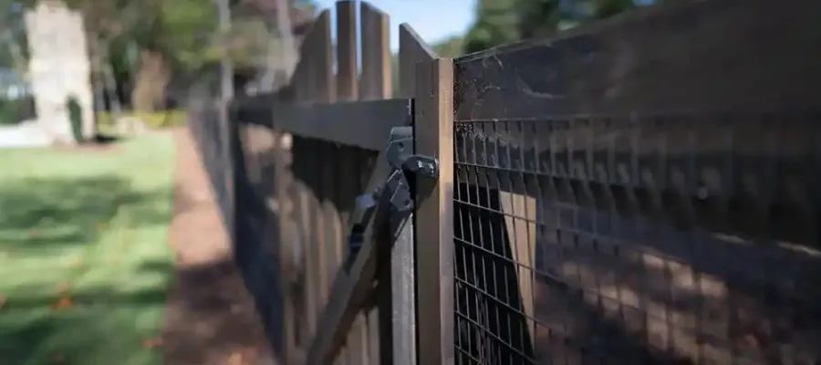 a fenced in area with a stone wall and trees in the background