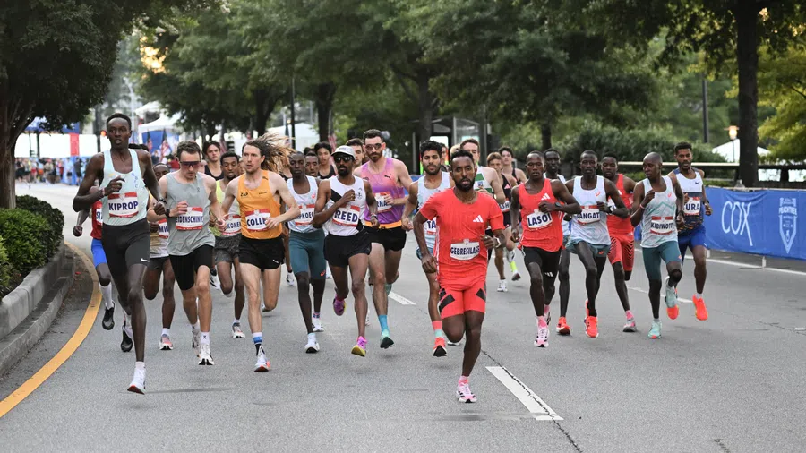 Group of diverse male runners competing in a marathon on a tree-lined city street during daytime.