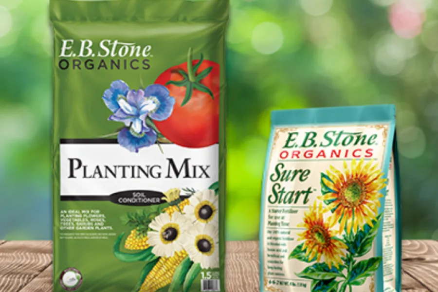 E.B. Stone Organics Planting Mix and Sure Start fertilizer bags with floral and vegetable illustrations on wooden surface.