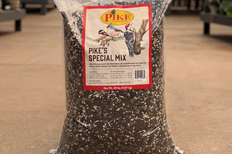 Large 20 lb bag of Pike's Special Mix birdseed with illustrations of birds on the label in a garden center.