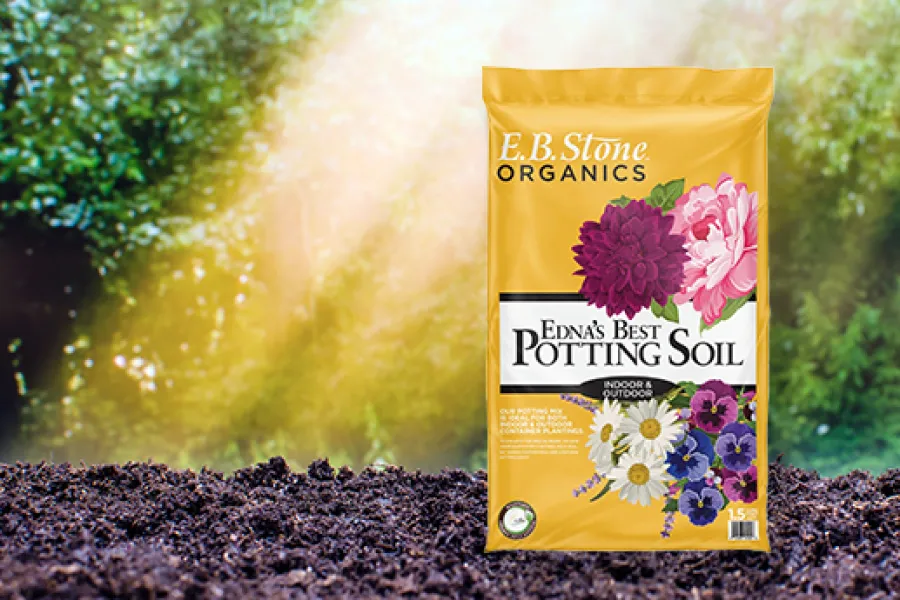 Bag of E.B. Stone Organics Edna's Best Potting Soil on soil with colorful flowers on packaging and bright background.