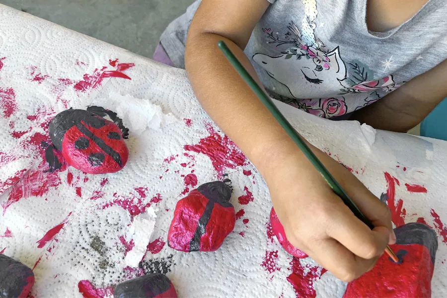 girl painting ladybug rocks