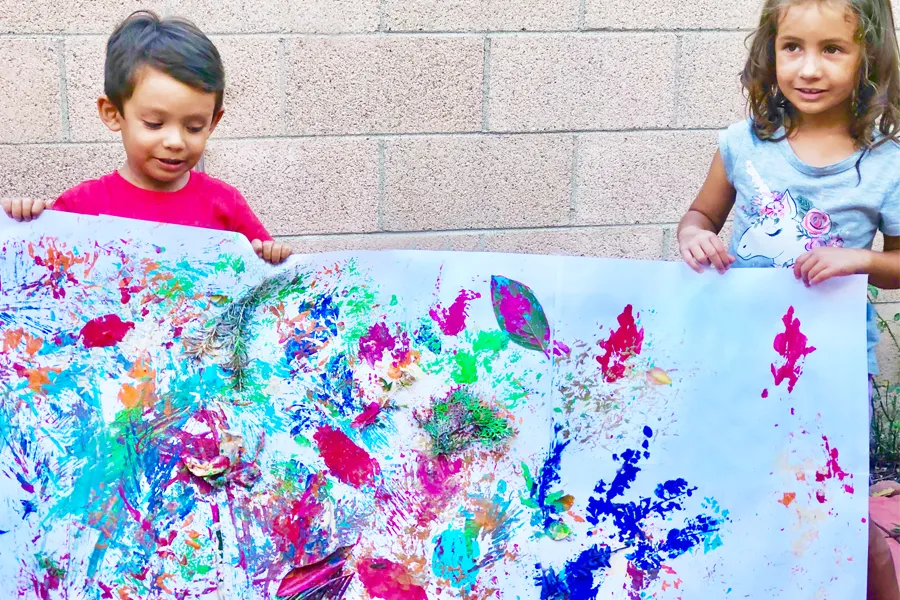 a girl and boy holding colorful nature paint artwork