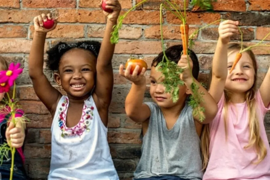 group of kids holding carrots and flowers from the garden