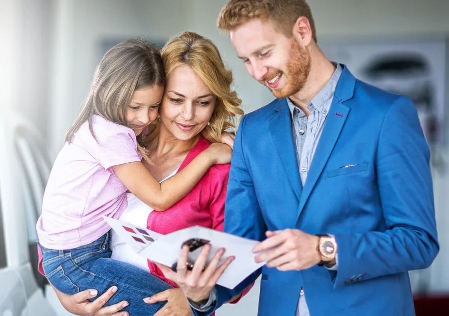 A man, a woman, and a child looking at a printed brochure