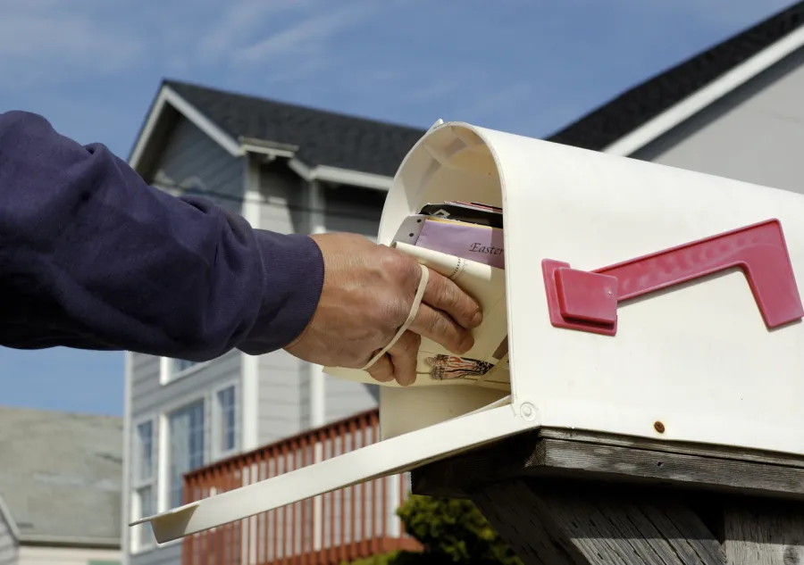 A mail carrier placing mail into a mailbox