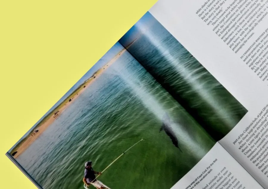 An open magazine with a Crossover Image of a fisherman spanning both pages