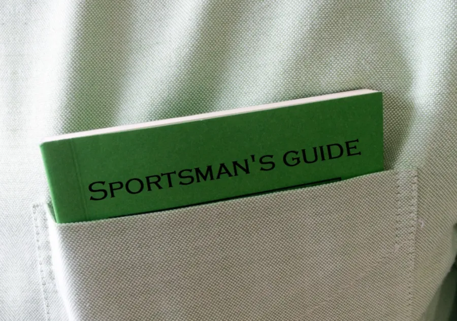 A small green and black guide book protruding from a shirt pocket