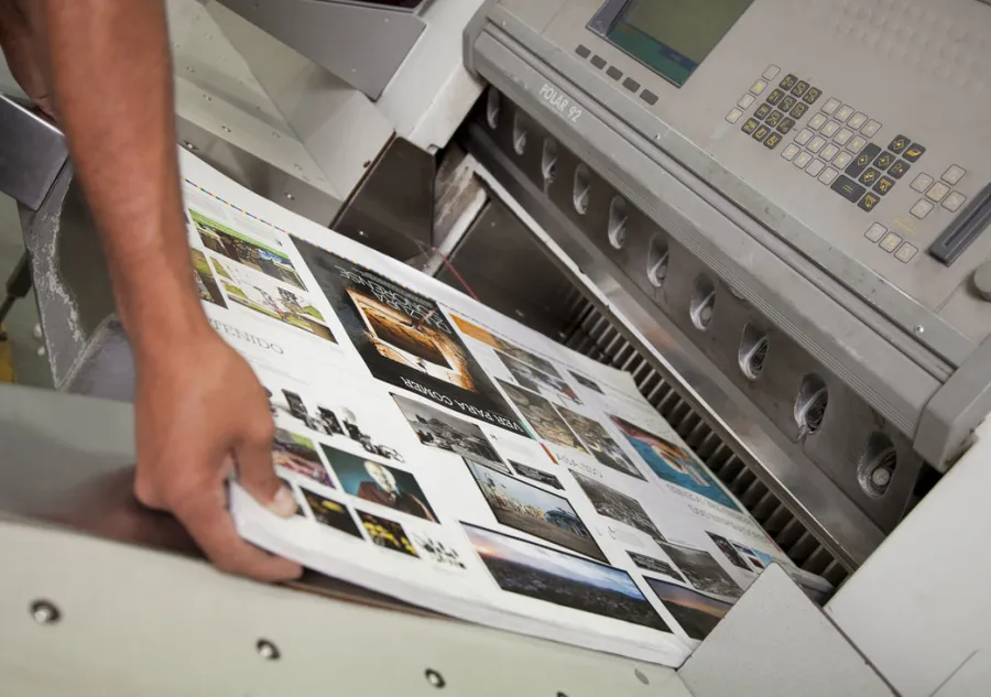 A hand holding a stack of printed sheets