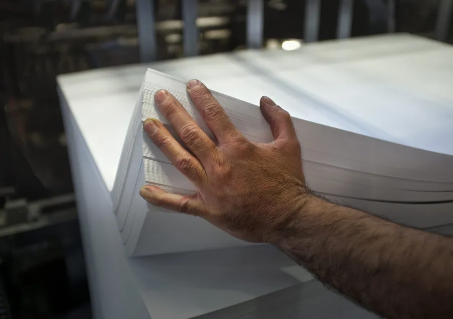 A male hand separating a large stack of paper sheets