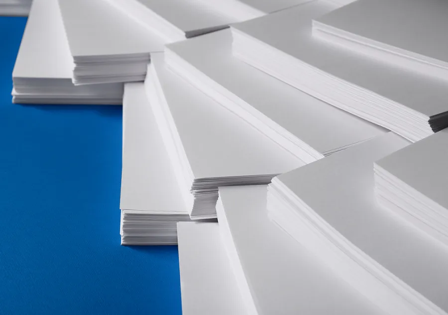 Stacks of large paper sheets lying on a blue surface