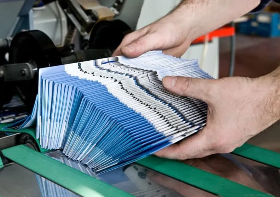 A stack of printed brochures exiting the folding machine