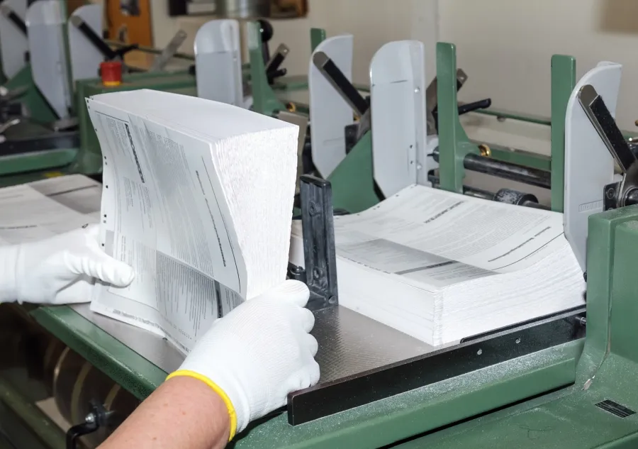 A commercial printing plant worker collating the sections of a book