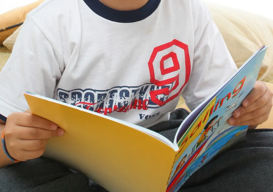 A boy holding open a softcover story book