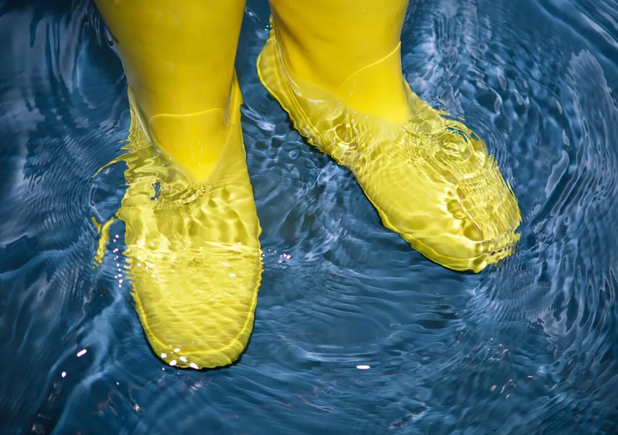A person wearing yellow rubber boots standing in water