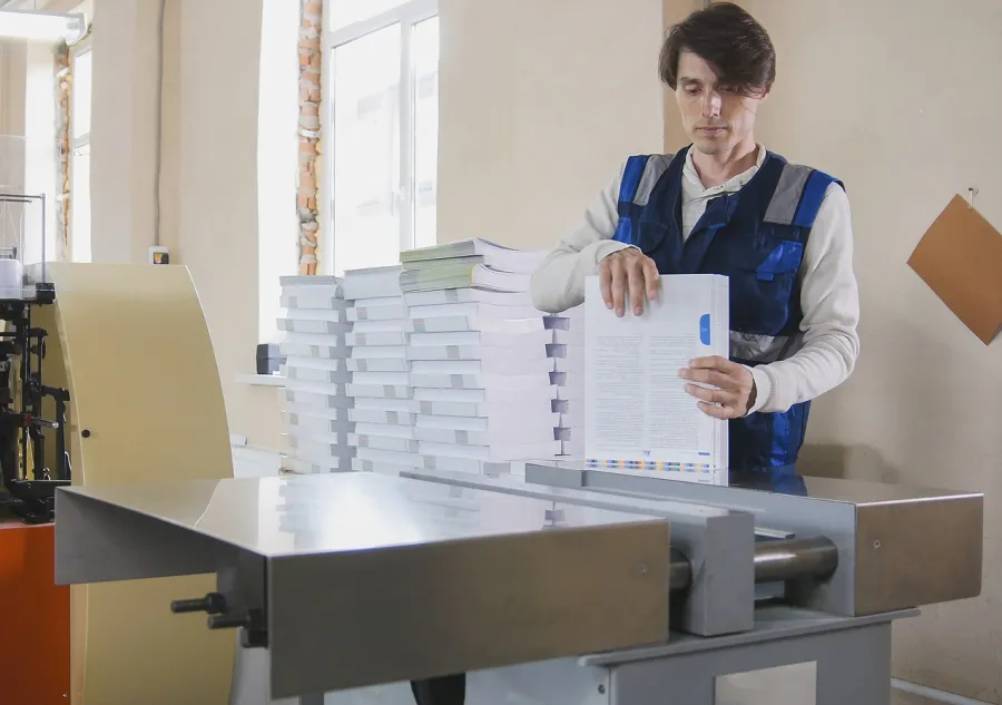 A print shop worker binding a short run of books