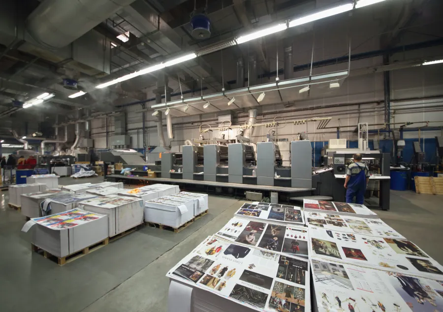 A variety of print projects on pallets in front of an offset printing press