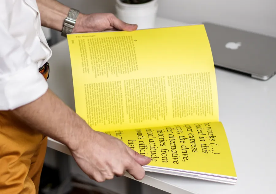 A person reading through a large book with yellow pages