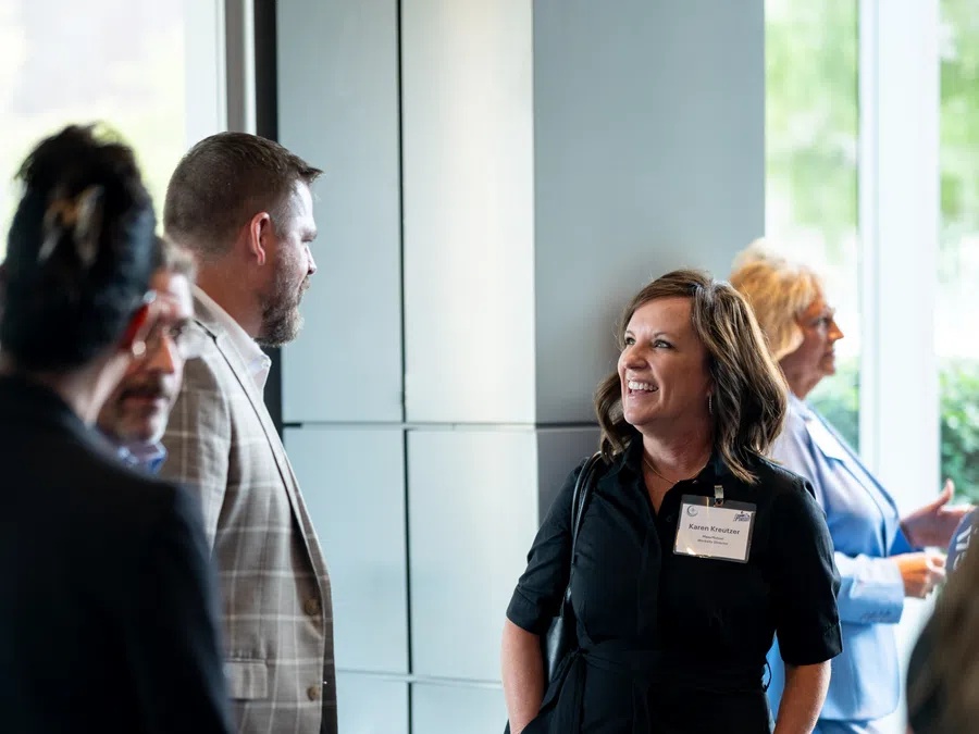 Business professionals networking and conversing during a conference or formal event in a modern indoor setting.