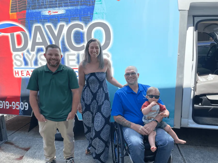 a group of people posing for a photo in front of a blue truck
