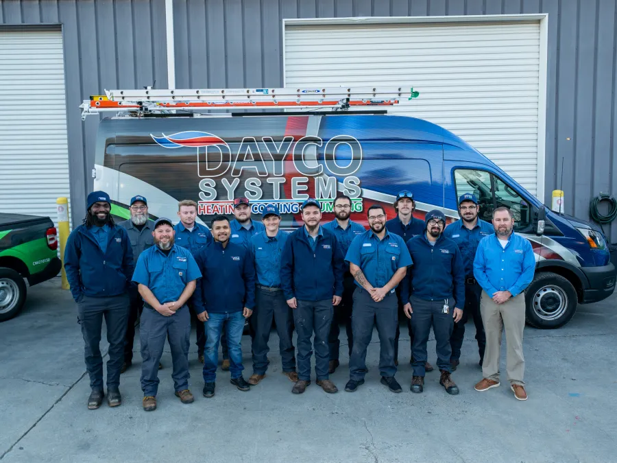 Team of Dayco Systems HVAC technicians standing in front of a branded service van at a warehouse.