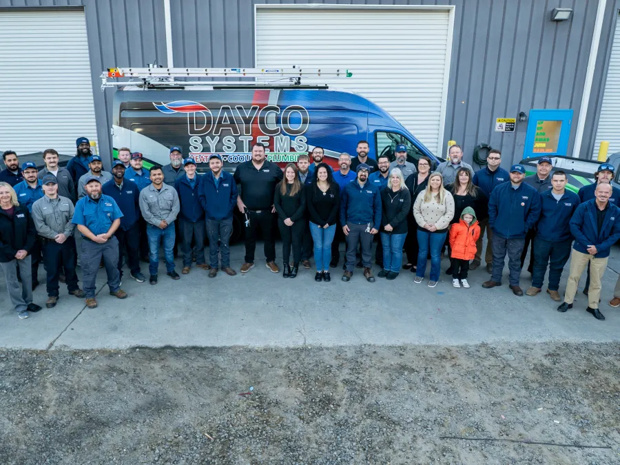 Large group of Dayco Systems employees standing outside building with company vans in the background.