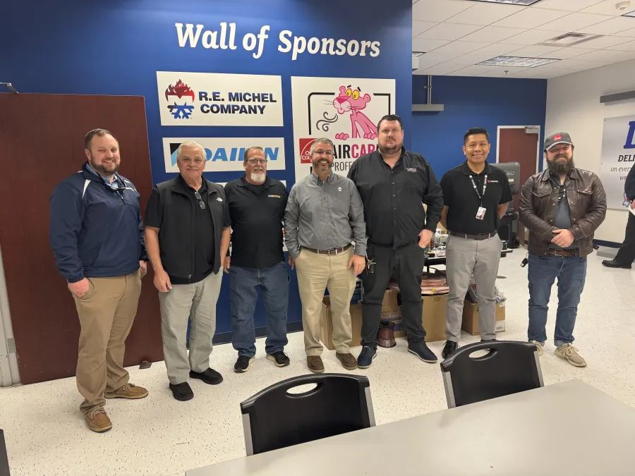 a group of men standing in front of a laptop