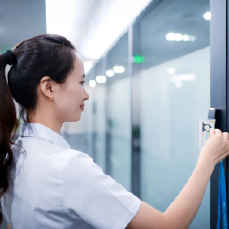 Woman in white shirt using key card to enter secure office door in modern hallway