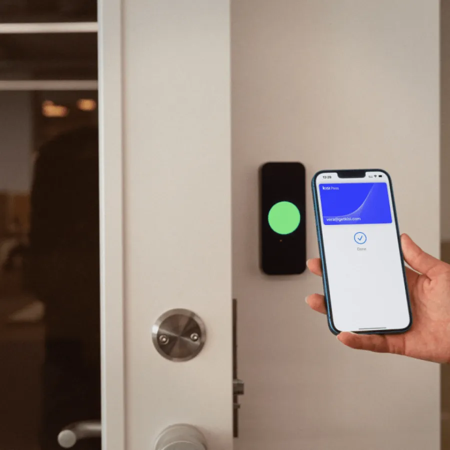 Person holding smartphone with digital key app unlocking a door with electronic access control system.