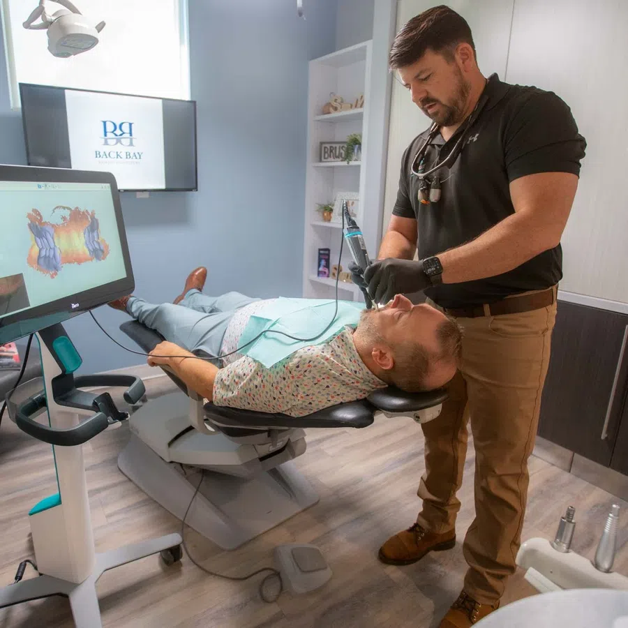 Dentist performing dental treatment on patient in modern clinic with digital imaging technology nearby