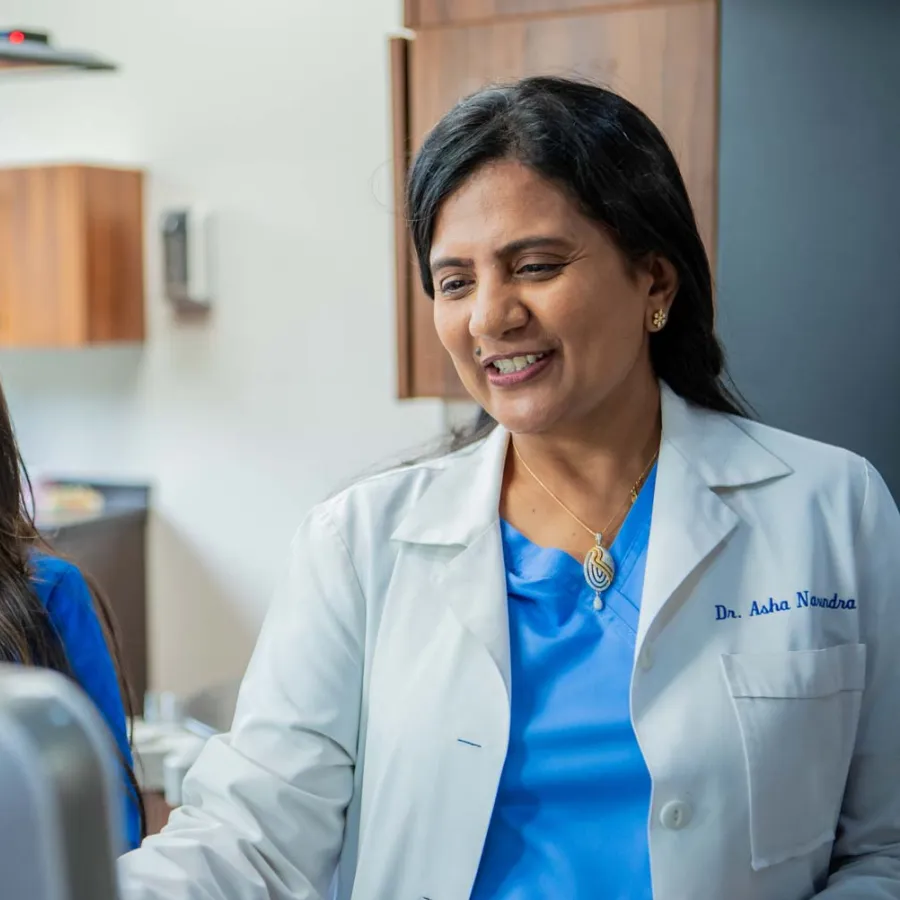 Female doctor and nurse reviewing medical information together on a computer in a clinic setting.