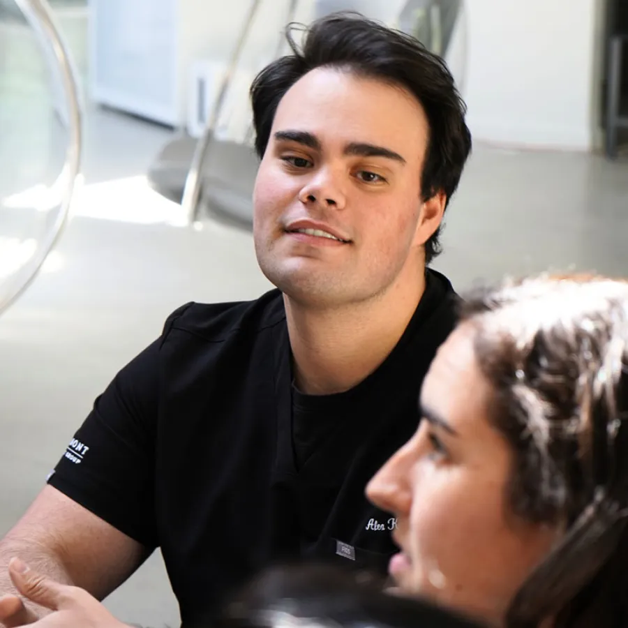 Young man in black medical scrubs engaged in conversation in a bright modern indoor setting
