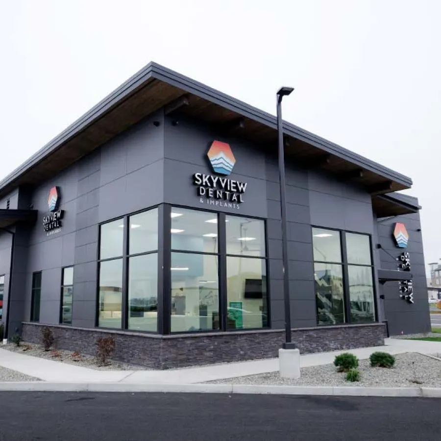 Modern Skyview Dental Implants building with large glass windows and clear signage on a cloudy day.