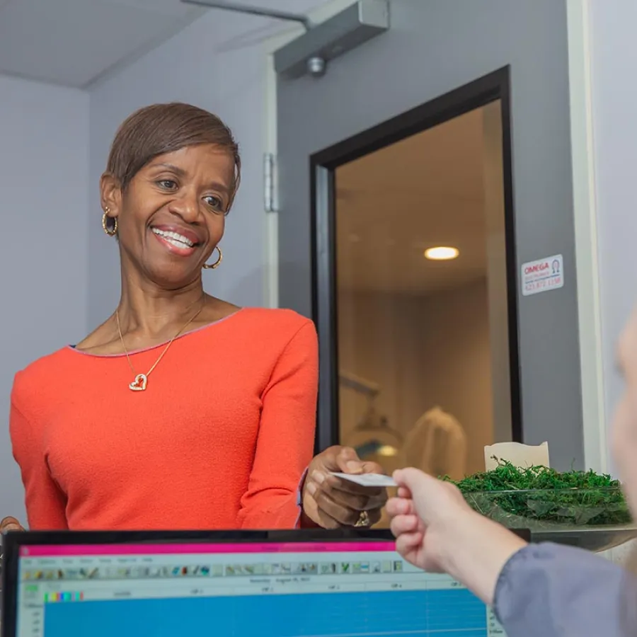 Dentist showing dental mold to elderly woman during consultation in bright dental office.