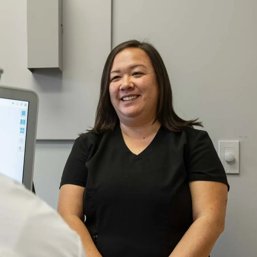 Smiling healthcare professional conversing with a patient in a modern clinical office setting.