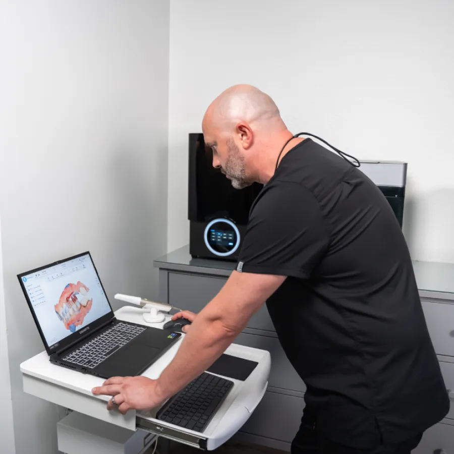 Dentist reviewing 3D dental scan on laptop in modern clinic with dental equipment in background