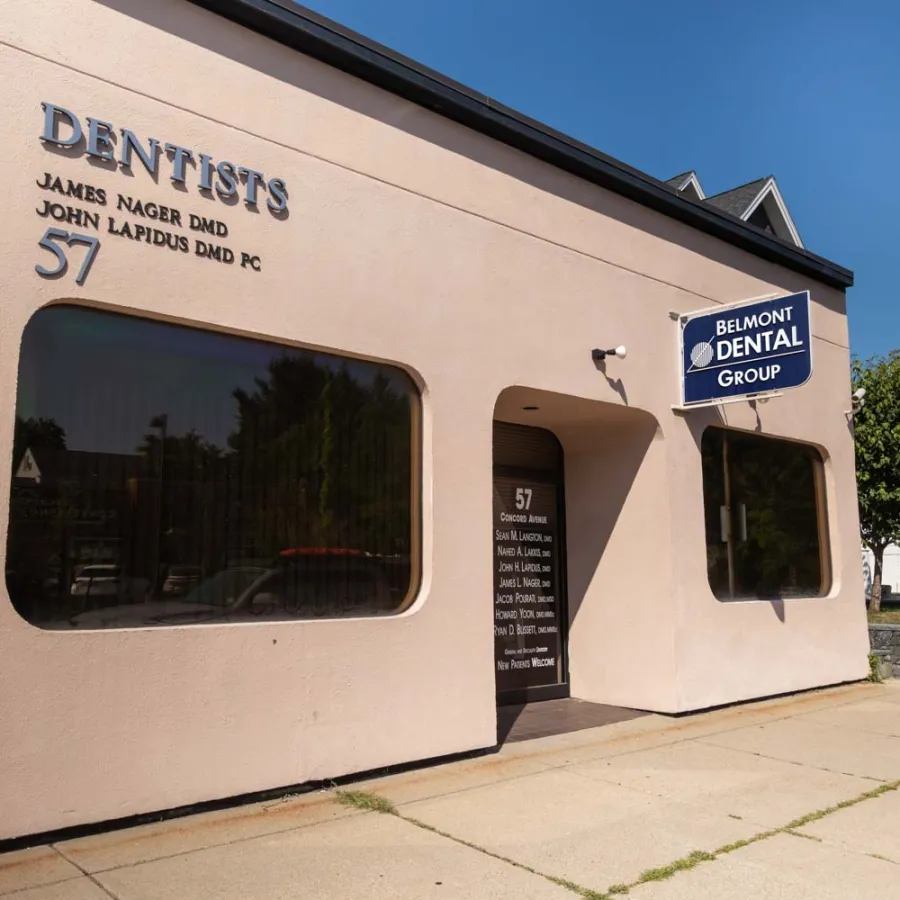 Exterior view of Belmont Dental Group with signage and address on a sunny day at 57 Concord Avenue