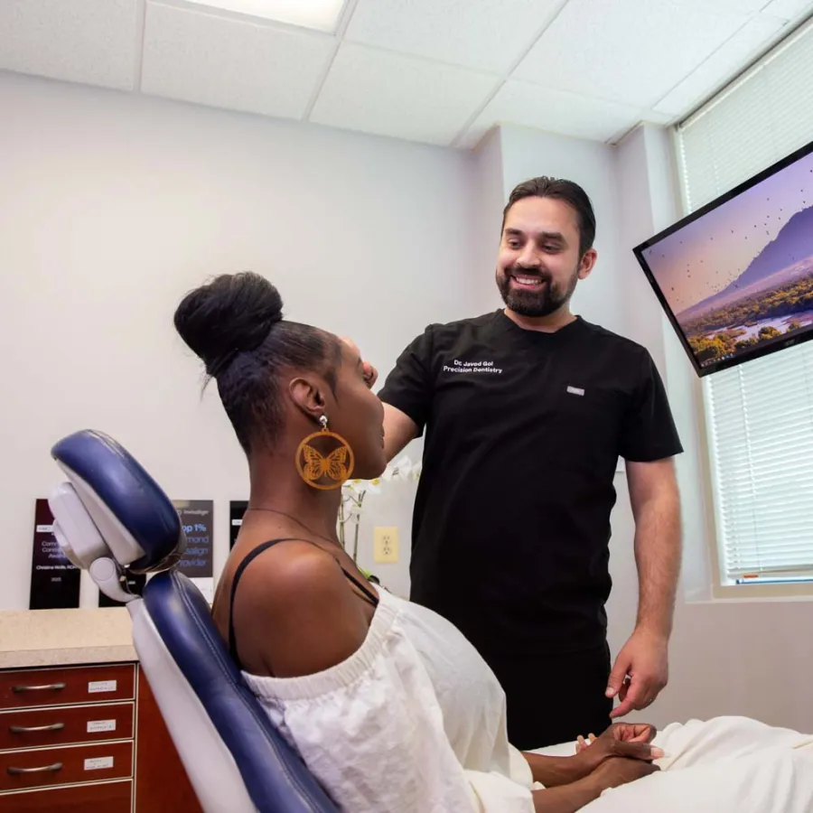 Dentist consulting with a female patient in a modern dental office with a scenic monitor display.