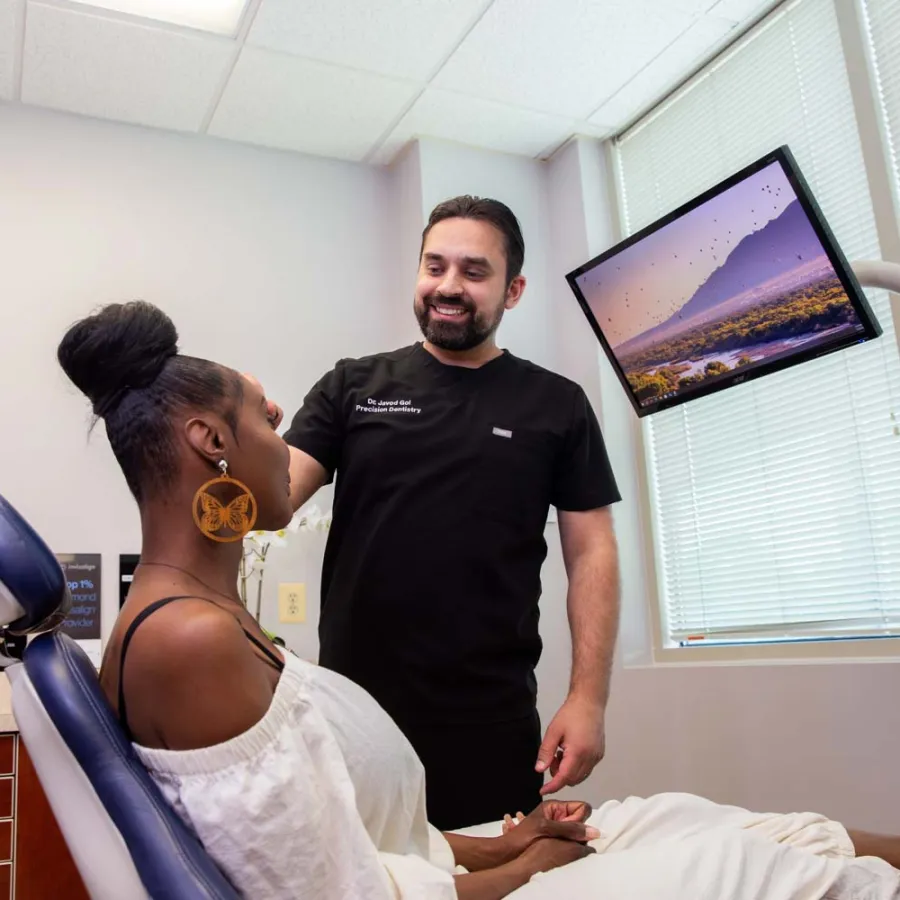 Dentist consulting with a female patient in a modern dental office with a scenic monitor display.