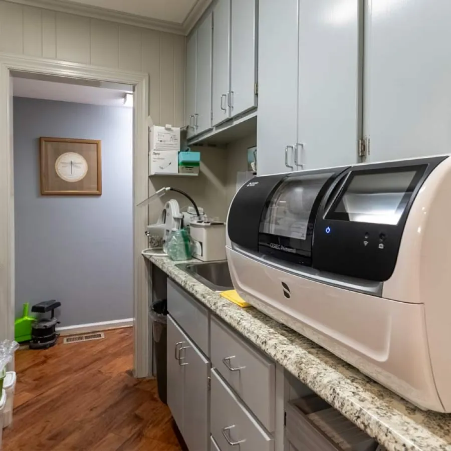 Dental office sterilization room with instrument cleaning machine, cabinets, sink, and countertop supplies.