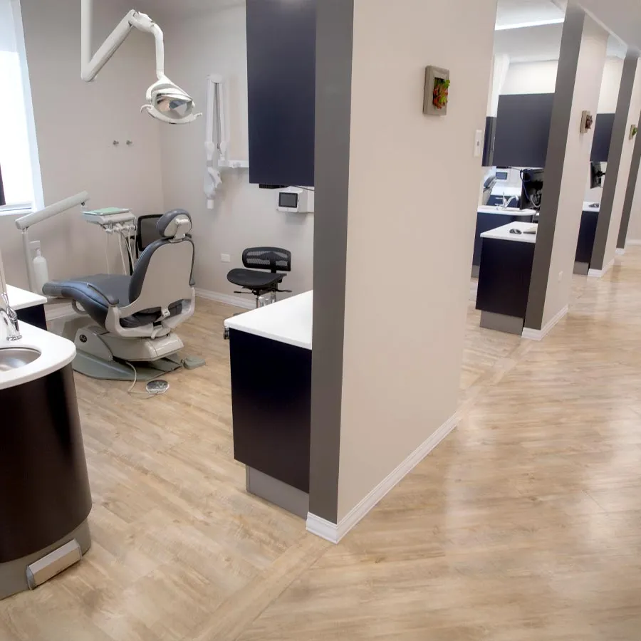 Modern dental clinic with multiple treatment rooms featuring dental chairs, equipment, and wood flooring.