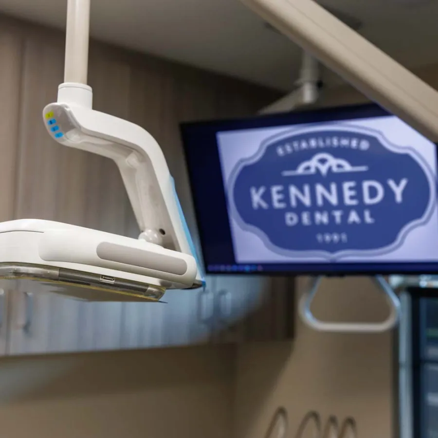 Modern dental X-ray machine and Kennedy Dental logo on screen in a dental office room