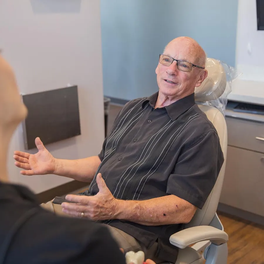 Dental hygienist explaining treatment plan to a smiling female patient in a modern dental office.