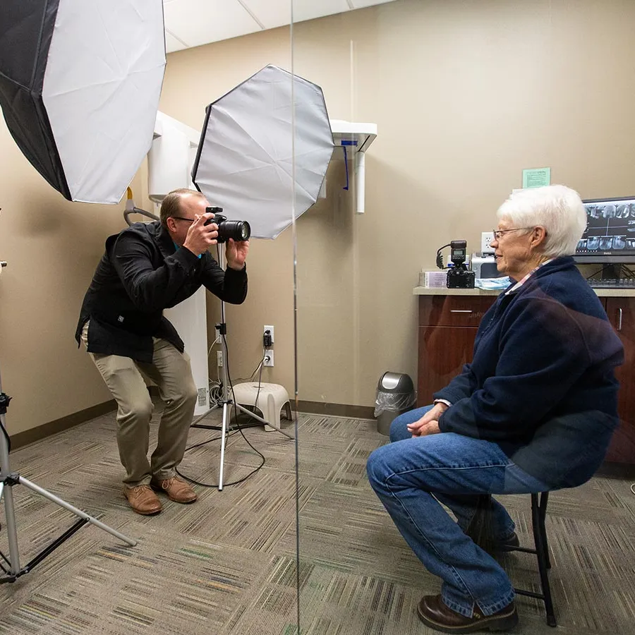 a person taking a picture of a person sitting in a chair